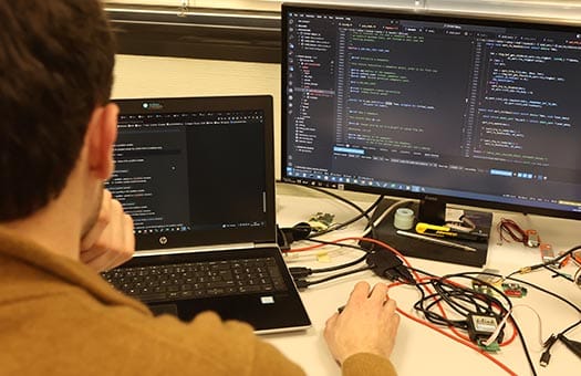 Photo montrant un développeur en train de coder sur on PC portable à double écran