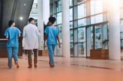 Une photo montrant plusieurs professionnels de la santé marchant dans un couloir d'hôpital.