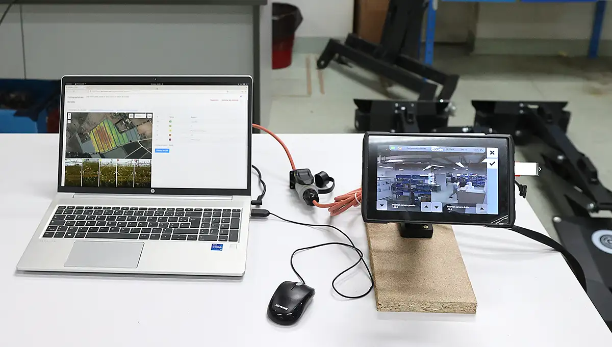 Photo montrant un PC de développement à gauche, posée sur une table, et une interface tactile IHM à droite sur un socle en bois